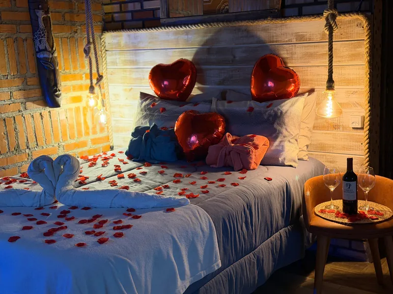 Cama de casal com pétalas e decoração romântica