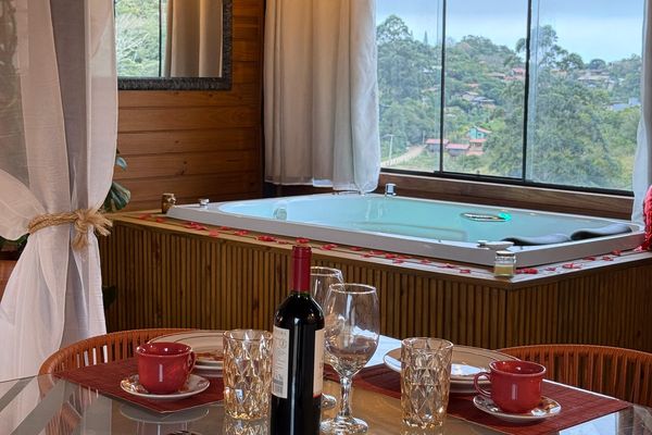 Mesa e hidromassagem junto à janela | Chalé Boutique dos Sonhos - Praia do Rosa/SC